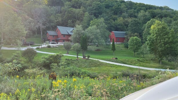 A rural landscape with a red barn and a house with a sloped roof. - River Valley Cabin (Lansing)