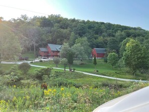 A rural landscape with a red barn and a house with a sloped roof. - River Valley Cabin (Lansing)