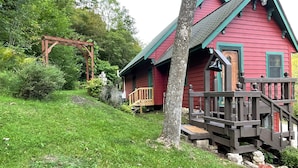 A red wooden house with a wooden porch and a staircase leading to a deck. - River Valley Cabin (Lansing)