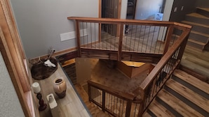 A wooden staircase with a railing, a chandelier, and a rustic decor including a skull and pottery. - River Valley Cabin (Lansing)