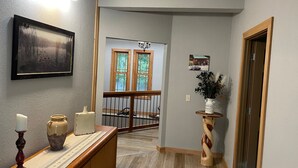 A hallway with a wooden bench, a vase, and a framed picture on the wall. - River Valley Cabin (Lansing)