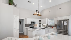 Una cocina moderna con armarios blancos, electrodomésticos de acero inoxidable y una isla central con asientos.