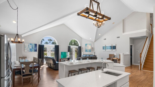 Una cocina amplia con una isla grande, piso de madera y un techo alto con candelabro.