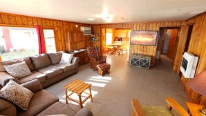 Ein Holzblockhaus-Innenraum mit Wohnzimmer, Essbereich und Küche.