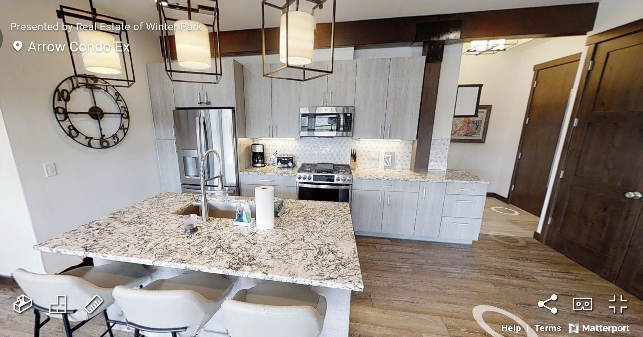 A modern kitchen with granite countertops, stainless steel appliances, and pendant lighting.