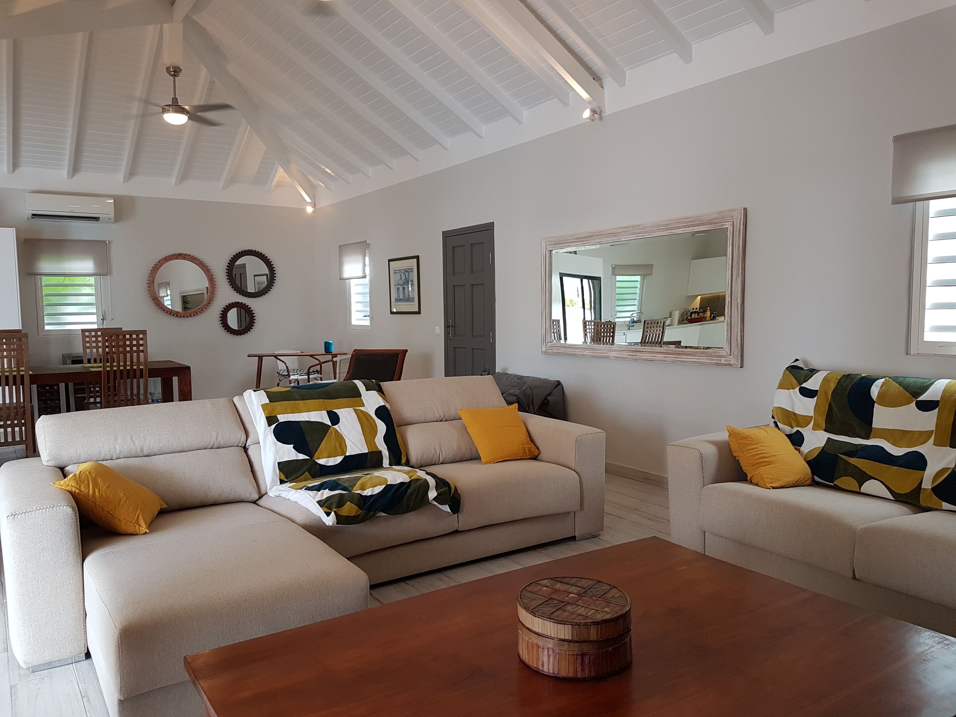 A spacious living room with two beige sofas, a wooden coffee table, and a large mirror on the wall.