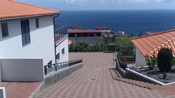 Ein gepflasterter Weg führt zu einem Gebäude mit roten Ziegeln, mit Blick auf ein Gewässer.