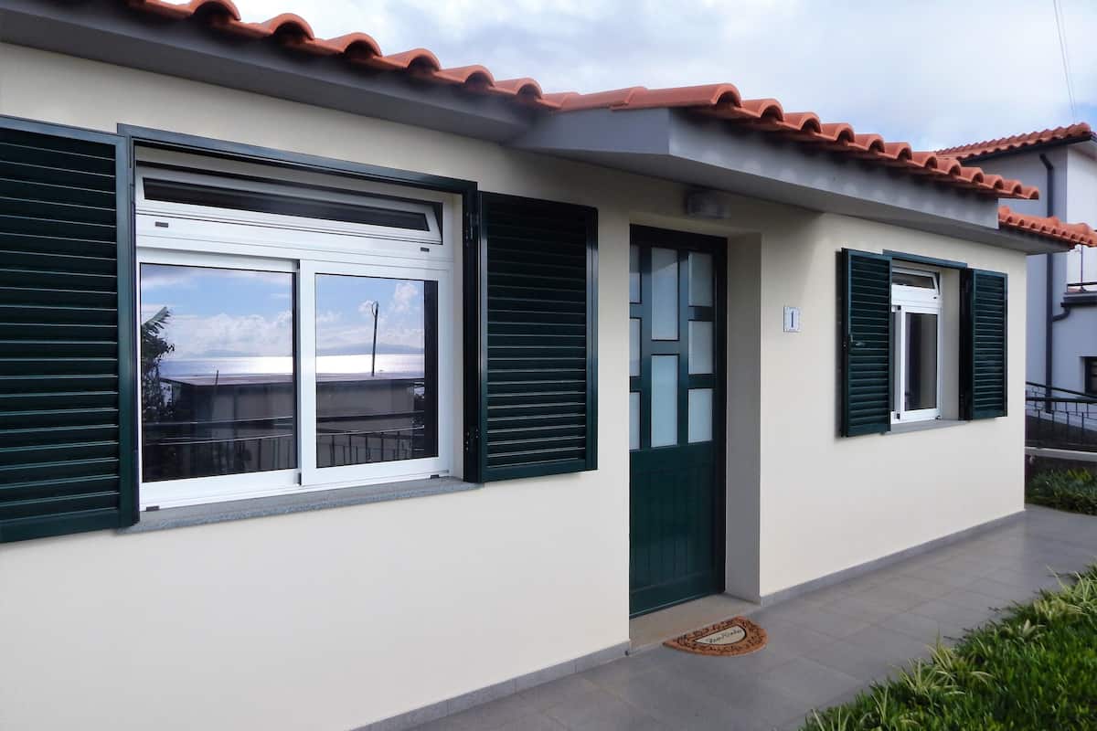 A building with a tiled roof, a door, and windows with shutters.
