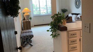 A hallway leading to a kitchen with a window, a lamp, and a potted plant. - Historic KMI Building - Condo, Park & Street View (Venice)
