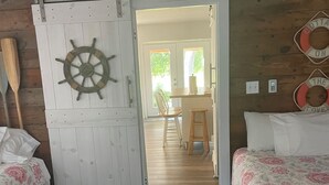 Ett rum med en säng, ett skrivbord och en stol. Det finns en dörr som är dekorerad med ett skeppsrat.