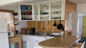 Ett kök med en köksö i trä, vita stolar och ett vitt kylskåp.