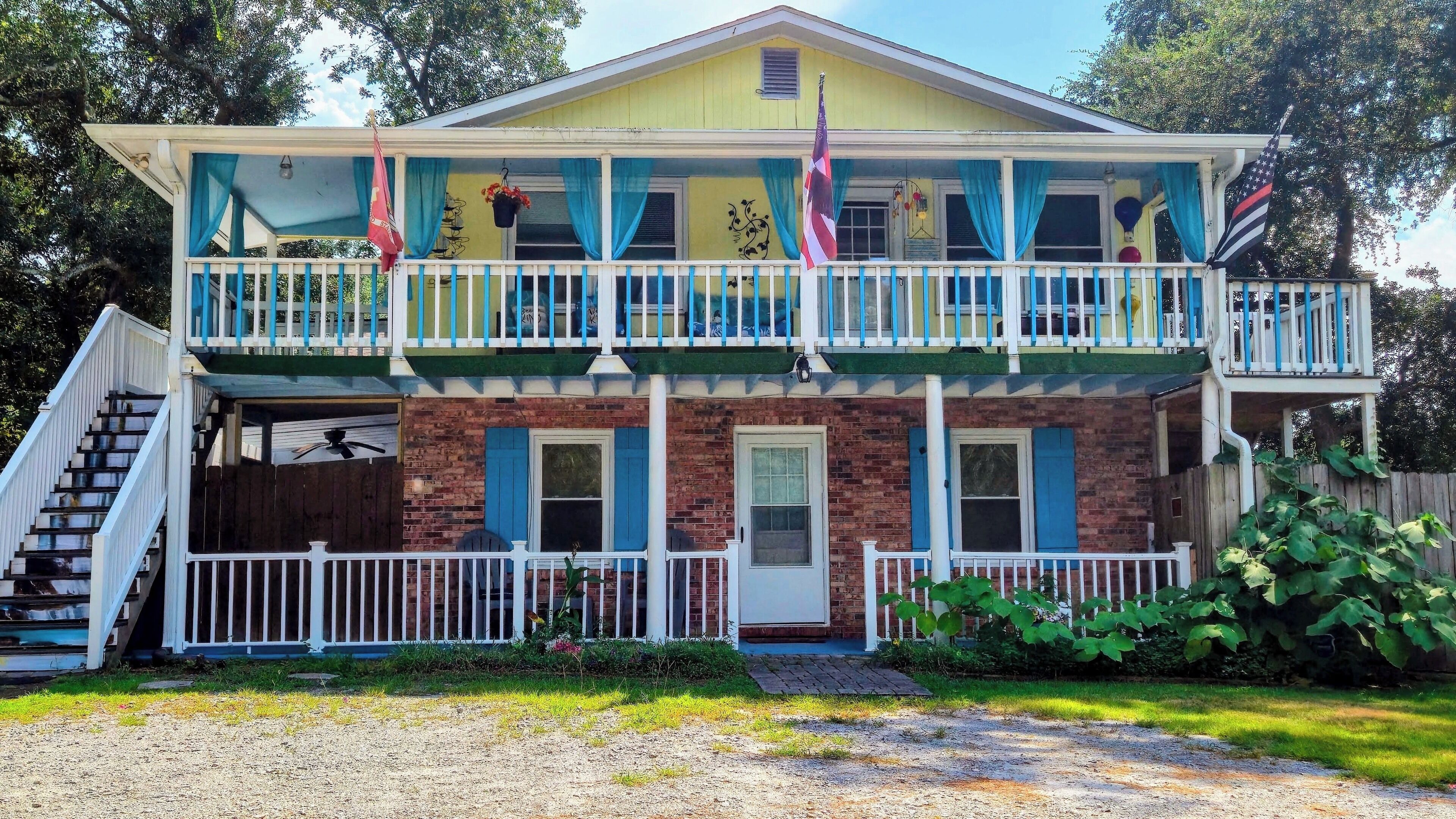 Une maison à deux étages avec un porche à l’avant, un escalier et un drapeau.