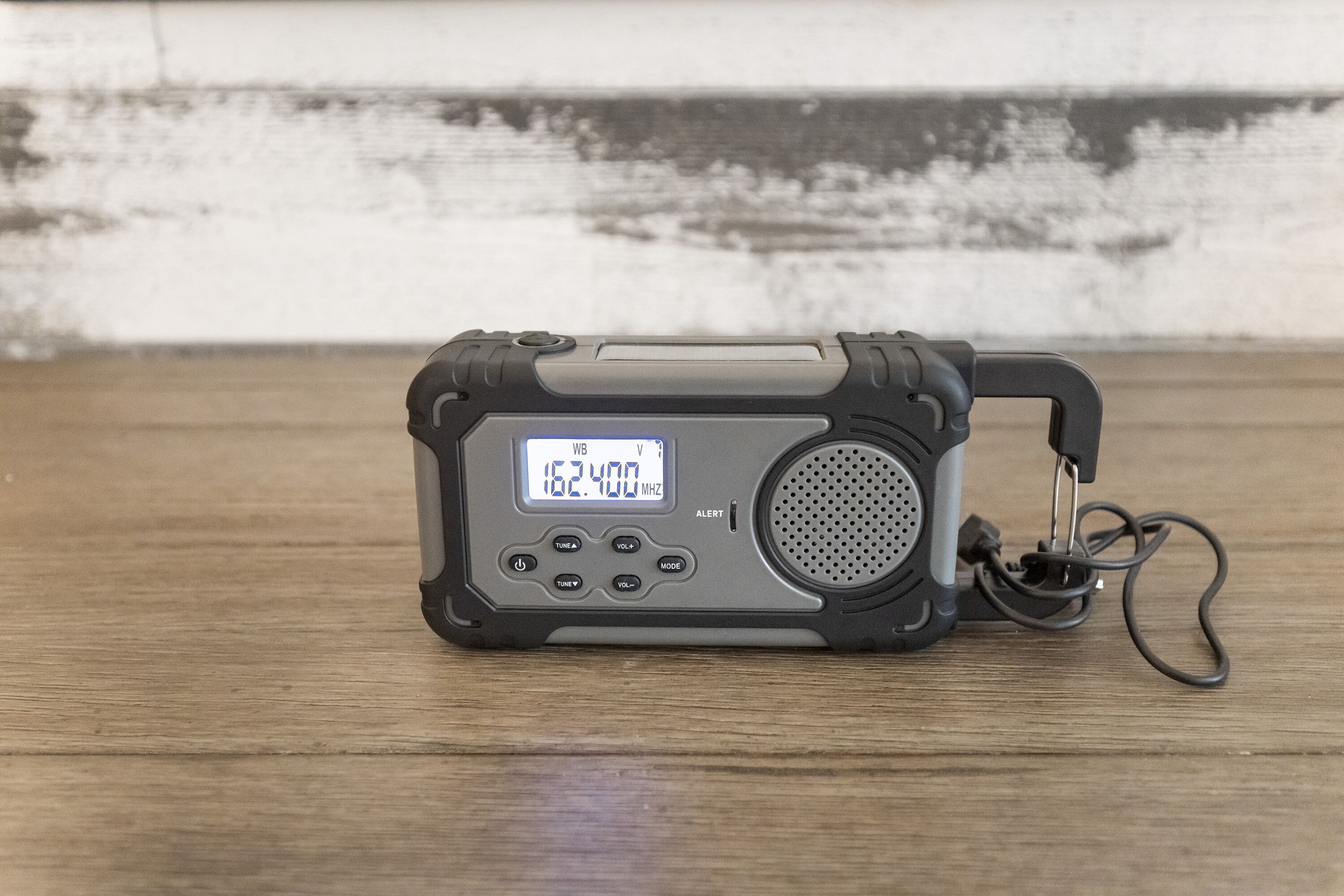 Une radio portable dotée d’un écran numérique, de boutons et d’un haut-parleur, posée sur une surface en bois.