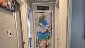 A hallway with a wooden floor leading to a door with a tropical mural. - PET FRIENDLY - MINUTES TO PARRIS ISLAND - BEACHES (Beaufort)