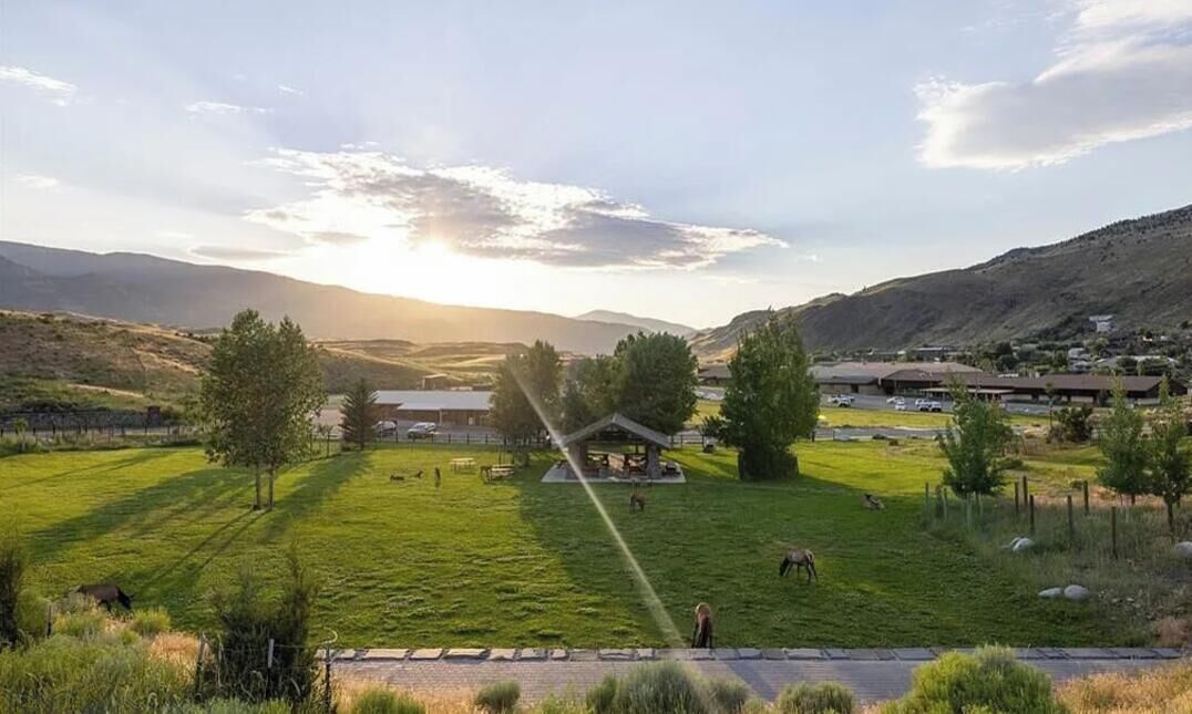 Een landelijk landschap met een prieel, open velden en heuvels in de verte.