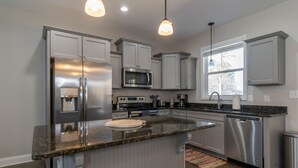 A modern kitchen with stainless steel appliances, grey cabinetry, and a granite countertop.