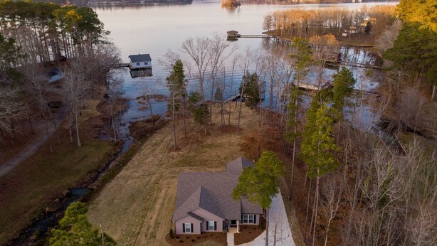 A house with a large yard, a dock, and a lake in the background.
