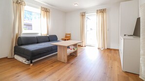 Un espace de vie compact comprenant un canapé, une petite table, une chaise et un téléviseur.