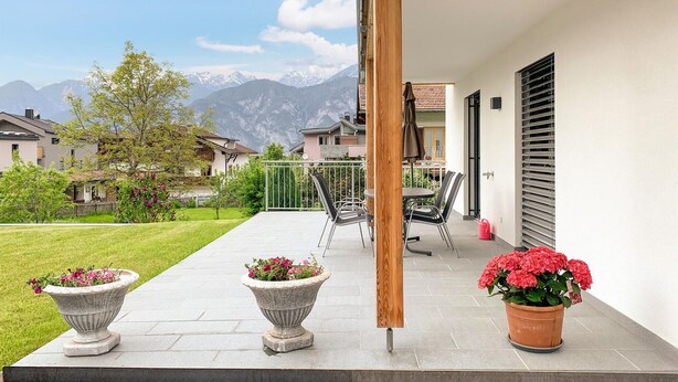 Un balcon avec vue sur les montagnes, un poteau en bois et des plantes en pot.