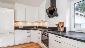 Une cuisine moderne avec des meubles blancs, un plan de travail noir et un four encastré.
