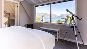 Un dormitorio con una cama grande, una ventana con vistas a la montaña, un telescopio y un radiador.