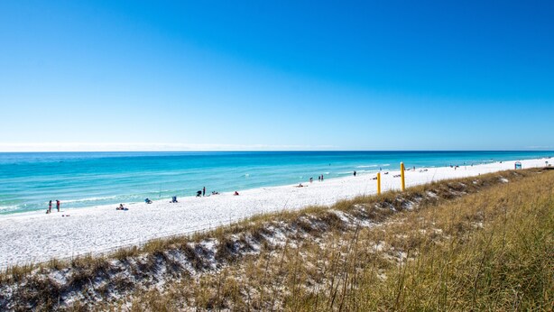 A beach with white sand and clear blue water.