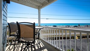A balcony with a view of the ocean and a road with cars.