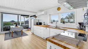 A modern kitchen with a large island, white cabinetry, and a view of the outdoors.