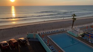 A beach view with a swimming pool and lounge chairs.