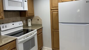 A kitchen with a stove, microwave, oven, and refrigerator.