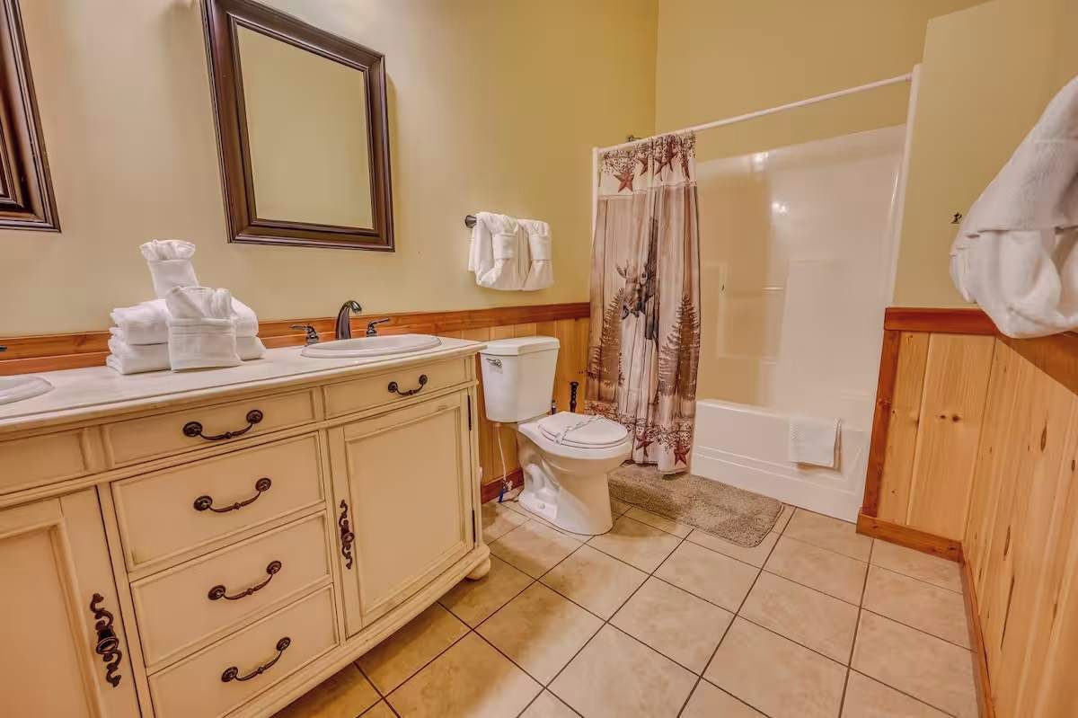 A bathroom with a vanity, sink, toilet, and shower curtain.