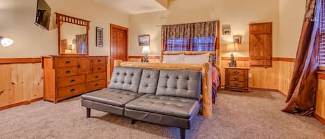 Une chambre avec un grand lit, des meubles en bois et un téléviseur fixé au mur.