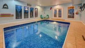 Una piscina interior con suelo de baldosas, ventanas y una puerta.