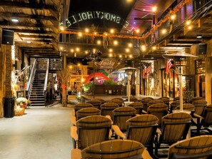 Un restaurante con sillas y mesas de madera, una escalera y un letrero de neón que dice "HOLLYWOOD".