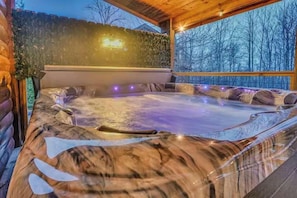Ein Whirlpool mit Holzterrasse und Blick ins Grüne.