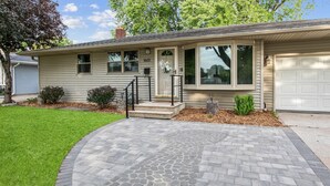 Une maison de plain-pied avec un porche à l’avant, un garage et une pelouse bien entretenue.