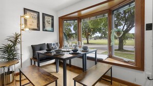 Un coin repas avec une table dressée pour quatre personnes, un banc et une plante en pot.