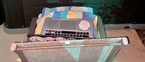 A hot tub with four people, a laptop on a chair, and a tray with drinks.
