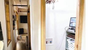 Ein schmales Dielen-Flur mit Deckenventilator und einer Tür zu einem Raum mit Computer und Regalen.