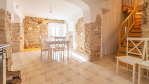 A spacious room with a stone wall, a wooden staircase, and a dining area with a table and chairs. - Nice home in Col with house a panoramic view (Col)