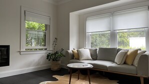 A living room with a grey sofa, a small round table, a potted plant, and a cowhide rug.