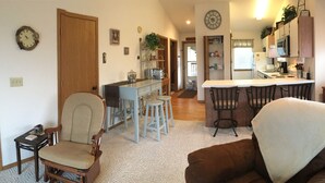 A cozy living room with a brown sofa, a wooden chair, and a small table with a lamp.