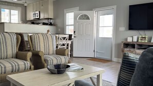 Un salon comprenant un canapé, des fauteuils, une table basse et un téléviseur.