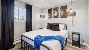 Ein Schlafzimmer mit einem Bett, zwei Nachttischen, einem Fenster mit Vorhängen und Wandbildern.