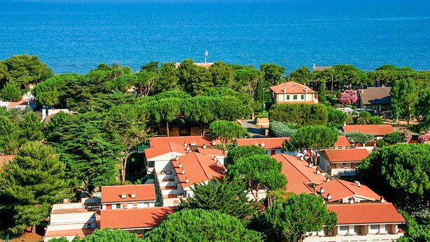 A coastal residential area with houses featuring red-tiled roofs, surrounded by dense green trees, and overlooking the sea. - Stunning apartment in Orbetello (Orbetello)