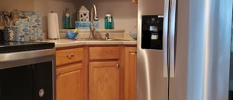 Una cocina con armarios de madera, un refrigerador de acero inoxidable, un microondas y un lavabo.