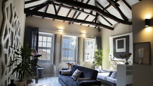 A cozy room with a dark blue sofa, a white dresser, and a large window.
