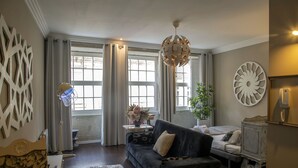 A living room with a dark blue sofa, a white round wall decoration, and a ceiling light fixture.