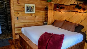 Un dormitorio de cabaña de madera con cama, almohadas y manta.