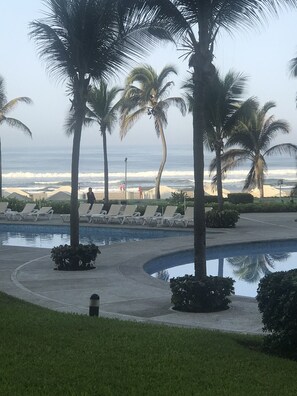 Relax by the oceanfront pool surrounded by lush greenery and palm trees.
